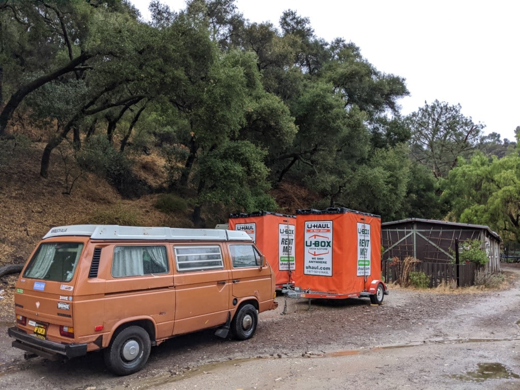 VW bus with two U Haul boxes and a home in the background