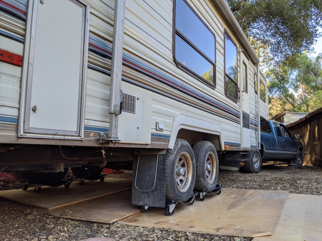 Fifth wheel trailer with it's tires on casters, hitched to a blue chevy truck